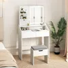 A white vanity table with a lighted mirror and a stool in a room with a bed and a plant. Anteprima dell’immagine prodotto
