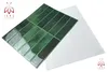 A set of green tiles is arranged diagonally on a white surface, with a white sheet of material behind them. A logo is visible in the top left corner. Produktbild-Vorschau