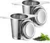 Two stainless steel tea infusers with lids and a small pile of loose leaf tea with a few green leaves. Produktbild-Vorschau
