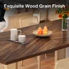 A dining table with a wood grain finish, set with a pitcher, cup, and a bowl of pears. The background shows a living room setting. Anteprima dell’immagine prodotto
