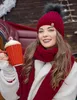 A woman in winter clothing holding a mug of hot chocolate. Voir les images du produit