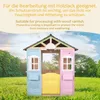 A colorful wooden playhouse set up in a grassy yard with trees and a blue sky in the background. Náhľad obrázku produktu