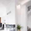A modern interior with a white wall, a ceiling light, and a plant. Náhľad obrázku produktu