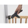 A hand is shown using a clamp to attach a wooden baby gate to a wall. Podgląd zdjęcia produktu