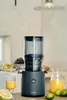 A Hurom slow juicer is on a kitchen counter, with a glass of juice and a pitcher of juice next to it. Podgląd zdjęcia produktu