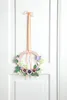 A decorative wreath with flowers and butterflies hanging on a white door. Produktbild-Vorschau