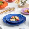 A table setting with multiple plates and cutlery, some with food. Náhled obrázku produktu