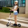 A young girl is riding a scooter on a crosswalk in front of a modern building. Podgląd zdjęcia produktu