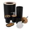 A set of black bathroom accessories with bamboo accents, including a trash can, soap dispenser, toothbrush holder, soap dish, tumbler, and toilet brush. Voir les images du produit