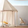 A child's play tent with pillows and a book inside, next to a wooden toy stroller. Produktbild-Vorschau