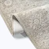 A close-up view of a rolled-up beige rug with a vintage pattern. Produktbild-Vorschau