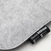 A close-up of a gray felt fabric with a black label attached. Produktbild-Vorschau