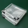 A folded transparent tarp with reinforced grommets and rope edging, displayed on a green surface. Voir les images du produit