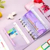 A flat lay of a purple binder with various inserts, including cash envelopes, a ruler, and a pen. Other decorative items and stickers are also visible. Voir les images du produit