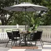 A patio set with a table, chairs, and an umbrella on a tiled patio, with a white lattice fence and greenery in the background. Anteprima dell’immagine prodotto