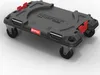 A black plastic transport platform with four wheels and red locking mechanisms, shown from a diagonal angle on a light gray background. Náhled obrázku produktu