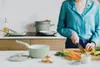 A person is cooking in a kitchen, with various pots and pans visible. Produktbild-Vorschau