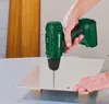 A person is using a cordless drill to make a hole in a metal sheet. Produktbild-Vorschau