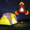 A tent is set up in a grassy field at night, with a starry sky above. A triangular warning light with a bright LED is shown in the upper right corner. Voir les images du produit