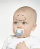 Close-up of a baby's head with a pacifier in its mouth. A black outline is drawn on the baby's forehead. Produktbild-Vorschau
