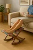 A person is relaxing on a couch with their feet on a footrest, holding a cup of tea. Produktbild-Vorschau
