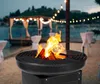 A fire pit with burning wood is shown on a beach at dusk, with a decorated event setup in the background. Produktbild-Vorschau
