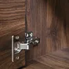 A close-up view of a cabinet hinge on a dark wood-grain surface. Produktbild-Vorschau