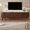 A modern living room scene featuring a TV stand with a television on top, a lamp, and a vase of flowers. Voir les images du produit