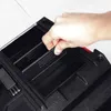 A hand is shown placing a small black organizer tray into a larger black toolbox. Náhled obrázku produktu