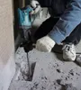 A person is using a rotary hammer drill to break up concrete. Produktbild-Vorschau