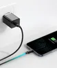 A black USB-C charger plugged into a white wall socket, connected by a black cable to a smartphone that is charging. Produktbild-Vorschau