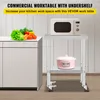 A commercial worktable with an undershelf is shown in a kitchen setting, with a microwave on the top shelf and a pot on the bottom shelf. Vegetables are on an adjacent cabinet. Podgląd zdjęcia produktu