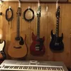 Several guitars and a keyboard are displayed against a wooden wall. Voir les images du produit