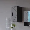 A modern bathroom cabinet with a geometric design is mounted on a tiled wall. Produktbild-Vorschau