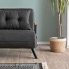 A close-up view of a dark grey sofa with a pillow, next to a potted plant on a wooden floor. Náhled obrázku produktu