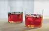 Two glasses of red liquid with floating ingredients on a wooden surface. Náhľad obrázku produktu