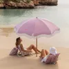 Two women relaxing on a beach under a pink umbrella. Produktbild-Vorschau