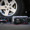 A car tire and a jump starter device are shown on a dark surface. Produktbild-Vorschau