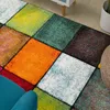 A close-up view of a colorful, geometric patterned rug with a teal armchair in the foreground. Produktbild-Vorschau