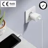 A white Apple USB-C power adapter is plugged into a wall socket, with a white Lightning cable connected to a black iPhone on a table. Náhľad obrázku produktu