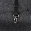 A close-up of a black fabric strap with a silver metal clip attached to a dark gray textured surface. Voir les images du produit