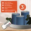 Three blue LED candles of varying heights on a gray tray, with a remote control in the foreground and a text overlay on the left. Voir les images du produit