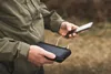 A person in an outdoor setting is holding a solar power bank and a smartphone, with the power bank connected to the phone by a cable. Anteprima dell’immagine prodotto