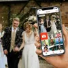A hand holding a smartphone displaying a photo album app, with a wedding scene in the background. Produktbild-Vorschau