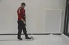 A man is using a roller tool on a white surface, possibly installing flooring or a protective layer. A large white radiator is visible on the wall. Produktbild-Vorschau