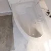Bild einer abgerundeten, weißen Badewanne in hellem Badezimmer mit einer seitlicheren Ansicht. Produktbild-Vorschau
