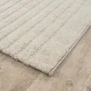 A close-up view of a textured rug with a striped pattern, placed on a wooden floor. Produktbild-Vorschau