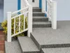 A set of stairs and a landing covered in a speckled stone carpet material, with a white railing and green shrubbery. Produktbild-Vorschau