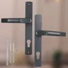 Two dark gray door handles with keyhole plates and some mounting hardware are displayed against a blurred background. Náhled obrázku produktu
