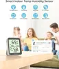 A family is in the background, while a smart temperature and humidity sensor is in the foreground on a table. There is also a graphic showing app data. Náhľad obrázku produktu